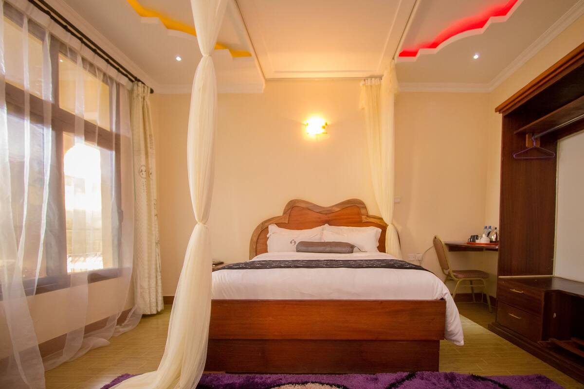 A bedroom with a wooden bed, a desk, and a wardrobe.