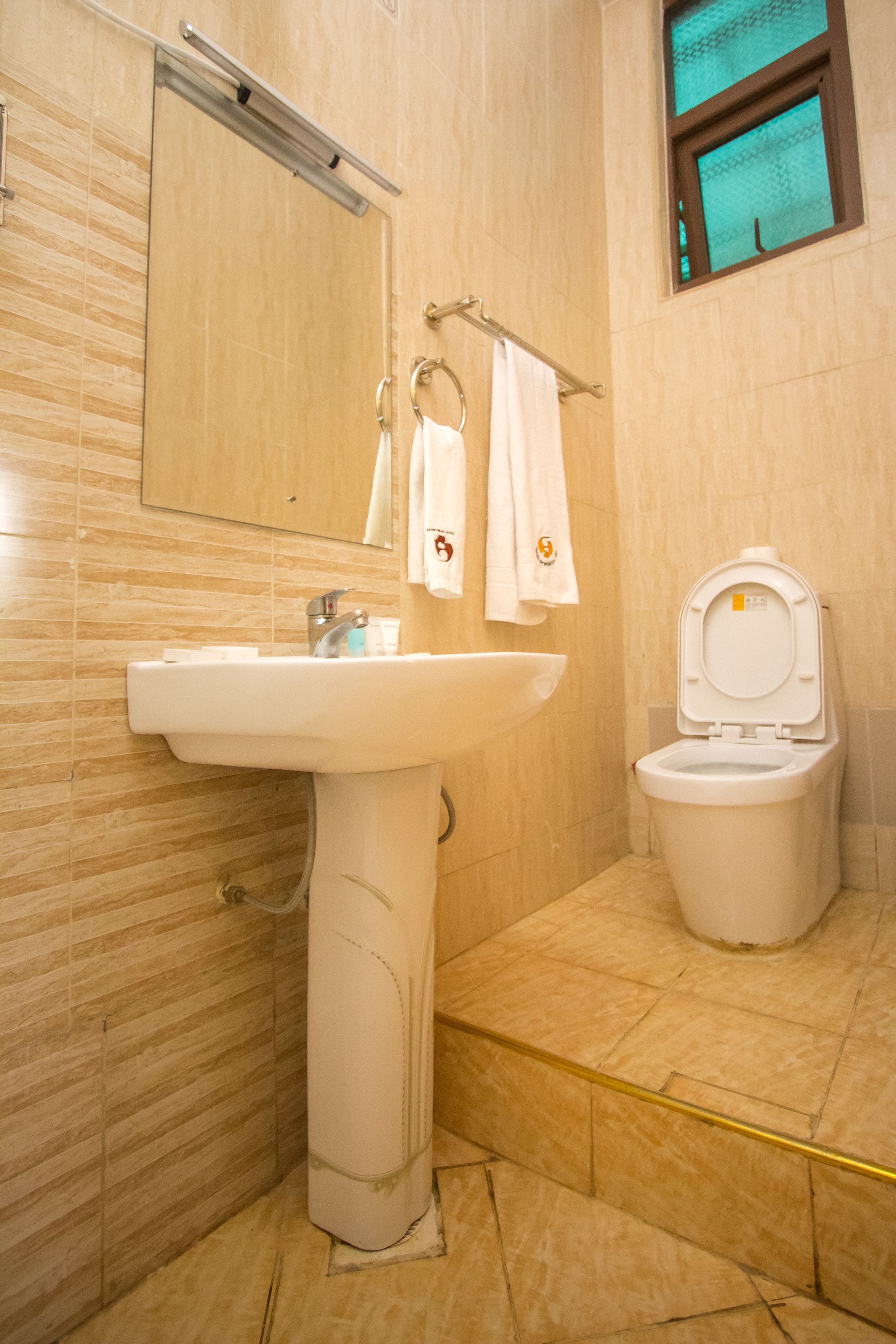 Ein Badezimmer mit einem Waschbecken auf Säule, Toilette und einem Spiegel über dem Waschbecken.