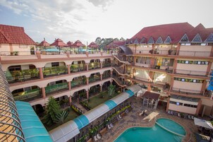 Un hotel de varios niveles con un patio central, piscina al aire libre y varios balcones.