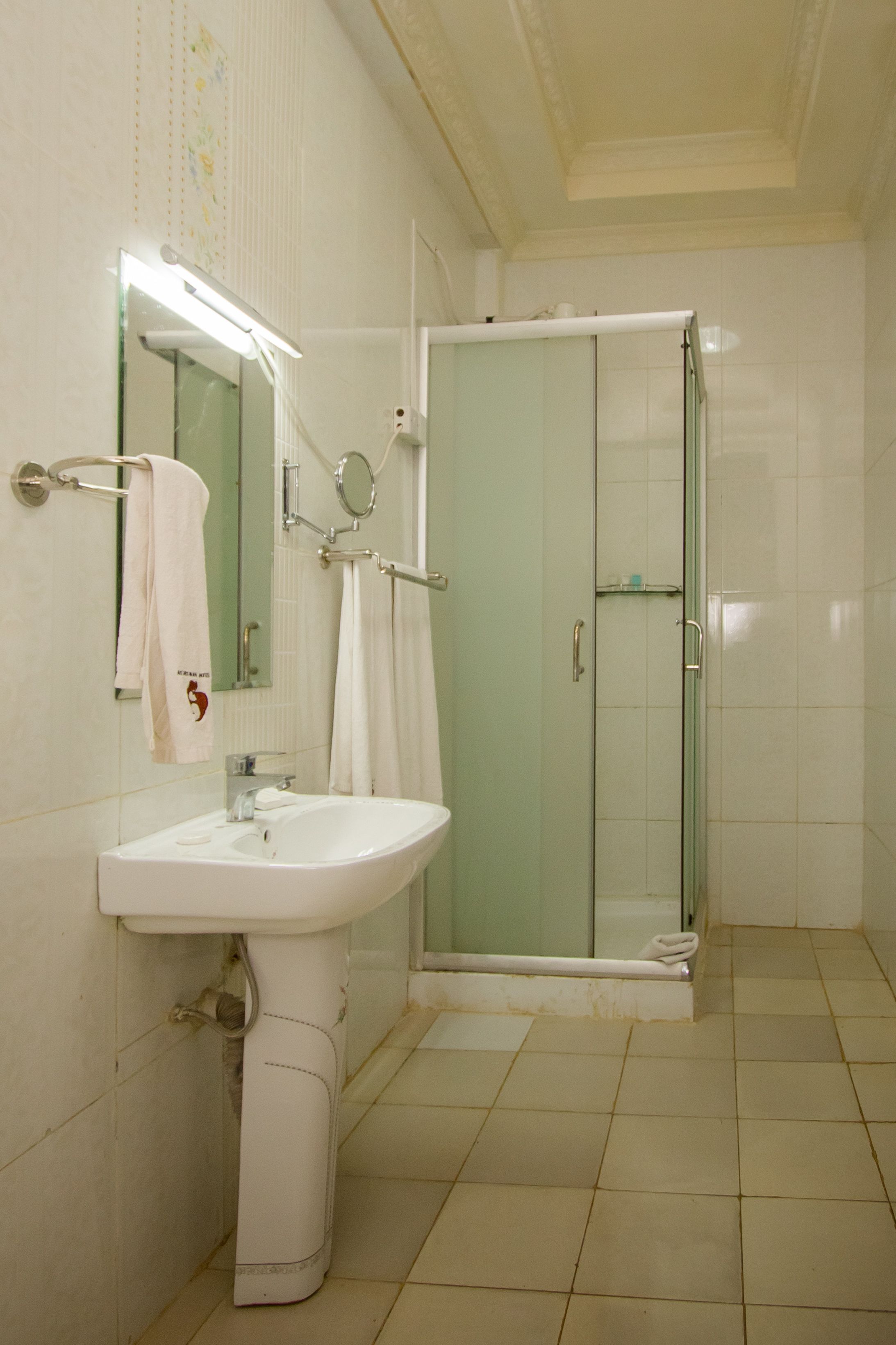 Ein Badezimmer mit Waschbecken, Spiegel und einer Duschkabine.