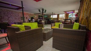 A bar area with wicker furniture and a television screen. - Balis Best Bar and Resort (Nairobi)