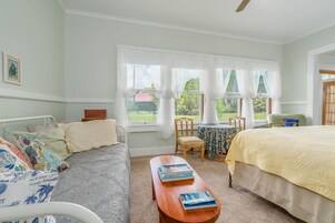 A bedroom with a bed, a sofa, a small table, and a window with curtains.