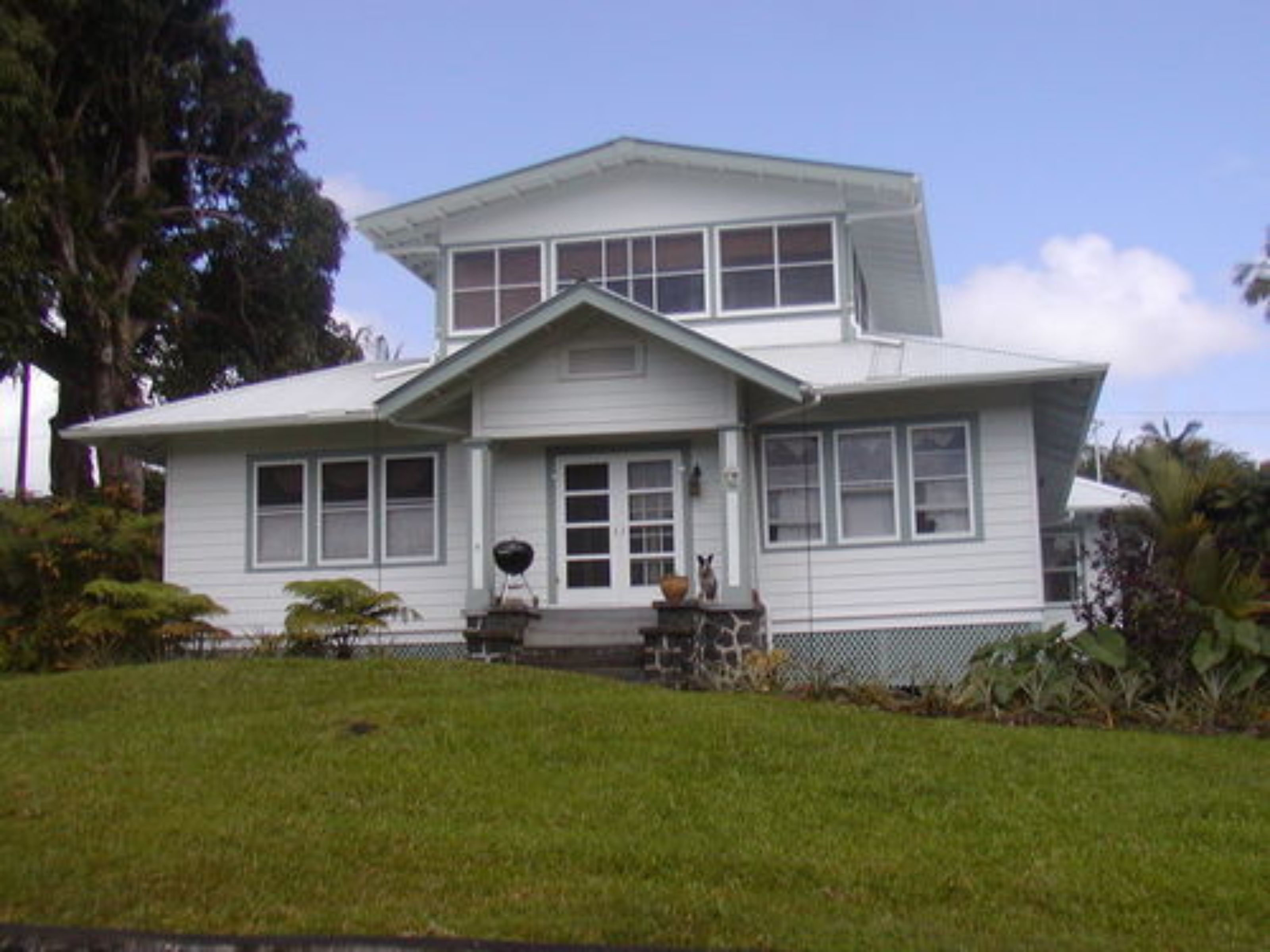 A two-story house with a front porch, large windows, and a well-maintained lawn.