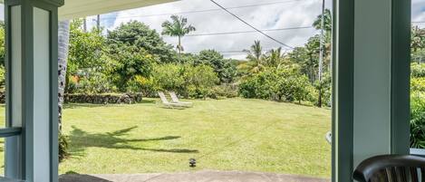 A covered patio area with a view of a well-maintained lawn and a few lounge chairs.