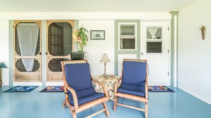 A room with two wooden chairs with blue cushions, a small table with a lamp, and a door with a wooden frame and glass panels. - Old Hawaiian B and B (Hilo)