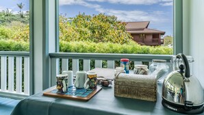 A table with kitchenware and a kettle on a balcony with a view of a house and greenery. - Old Hawaiian B and B (Hilo)