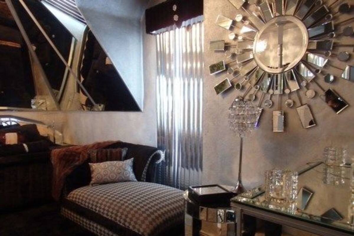 Quarto com cama, espelho, penteadeira e lustre.