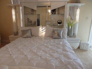A bedroom with a large bed, a mirror, and a vanity with shelves. - Central West End B&B (St. Louis)