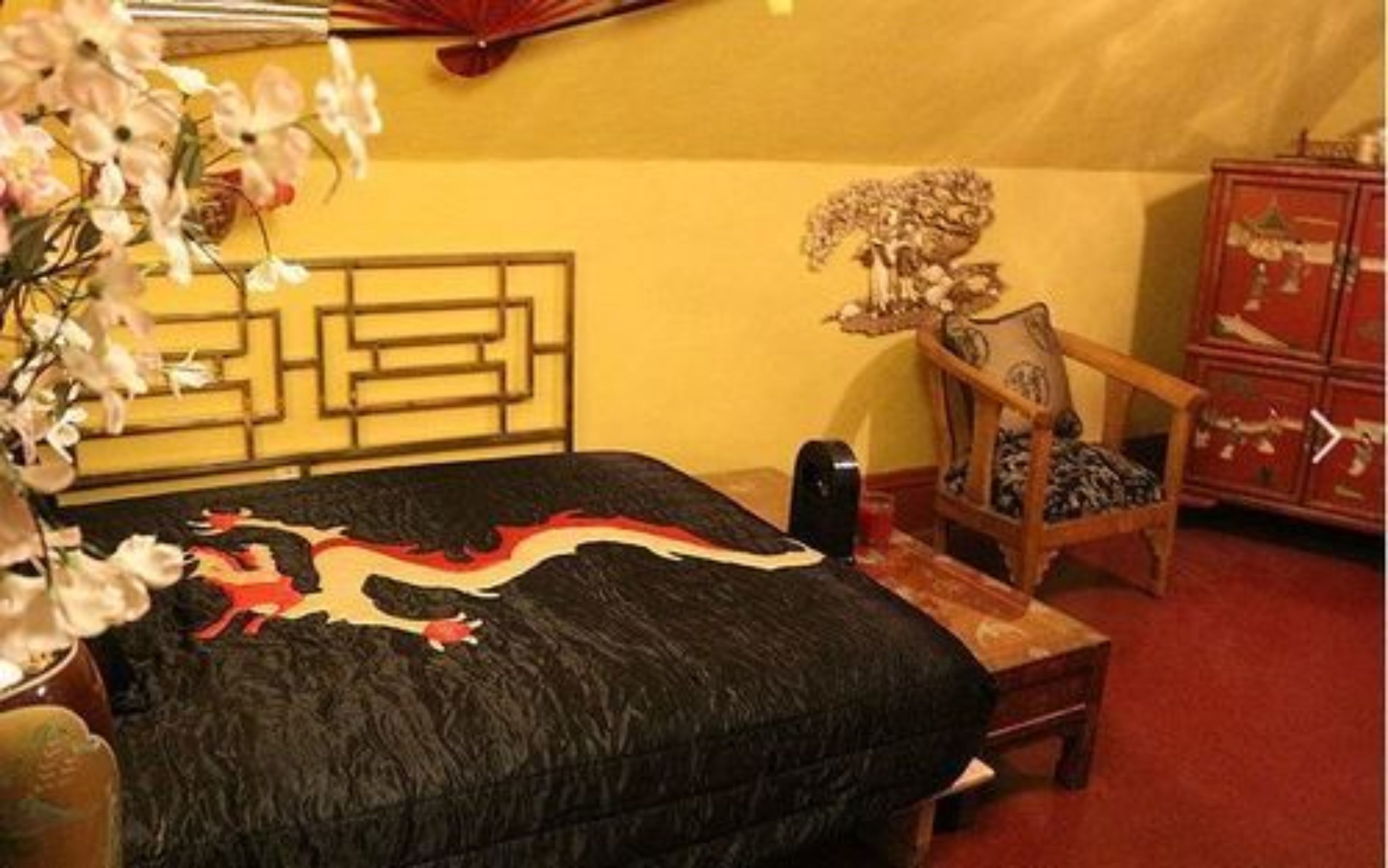 A room with a bed, a chair, a small table, and a cabinet.