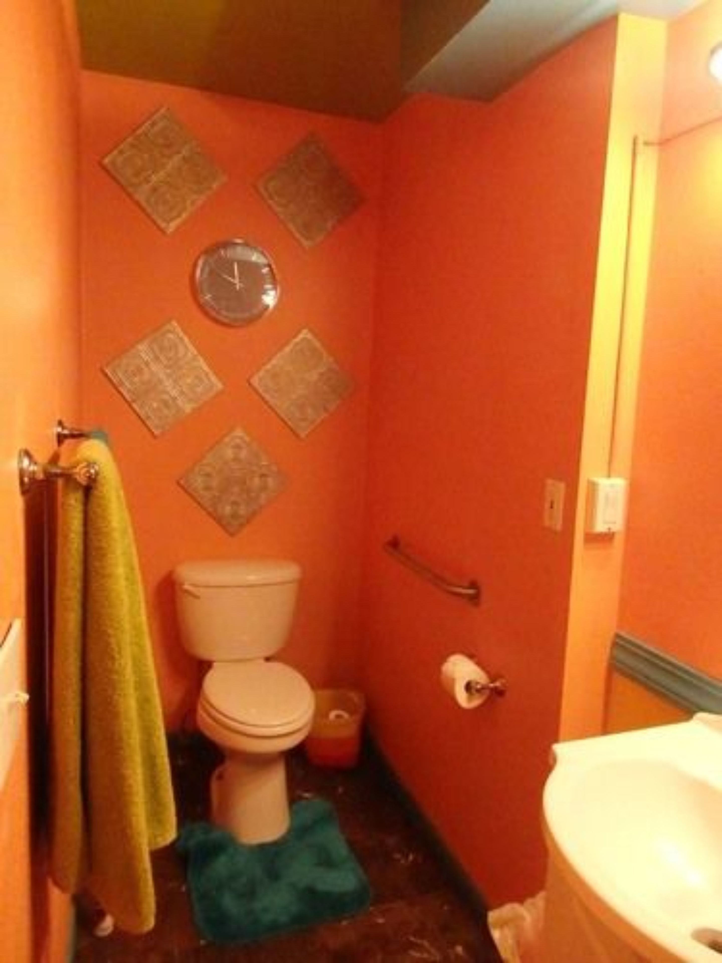 A bathroom with a toilet, a sink, and a clock on the wall.