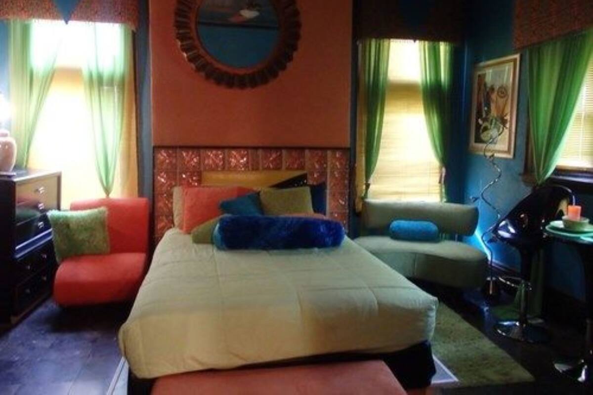 Quarto com cama, sofá e escrivaninha.