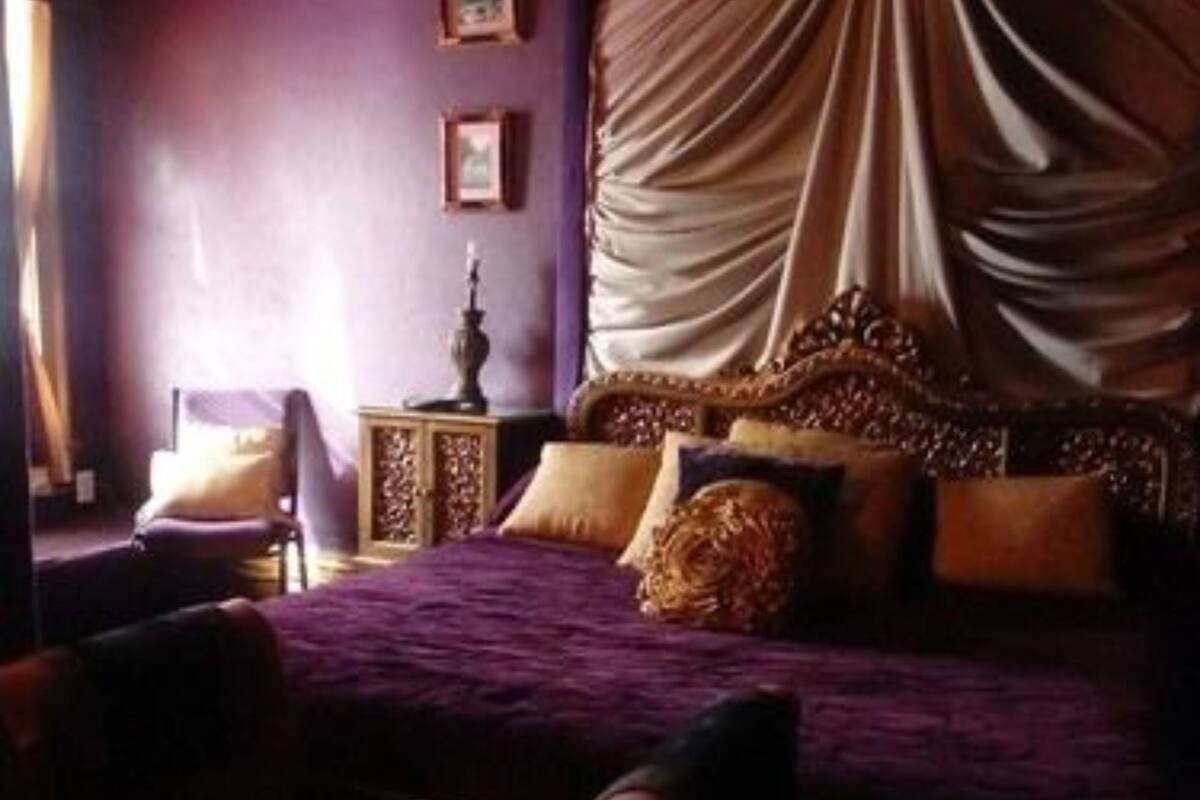Quarto com uma cama grande, roupa de cama roxa e um dossel.