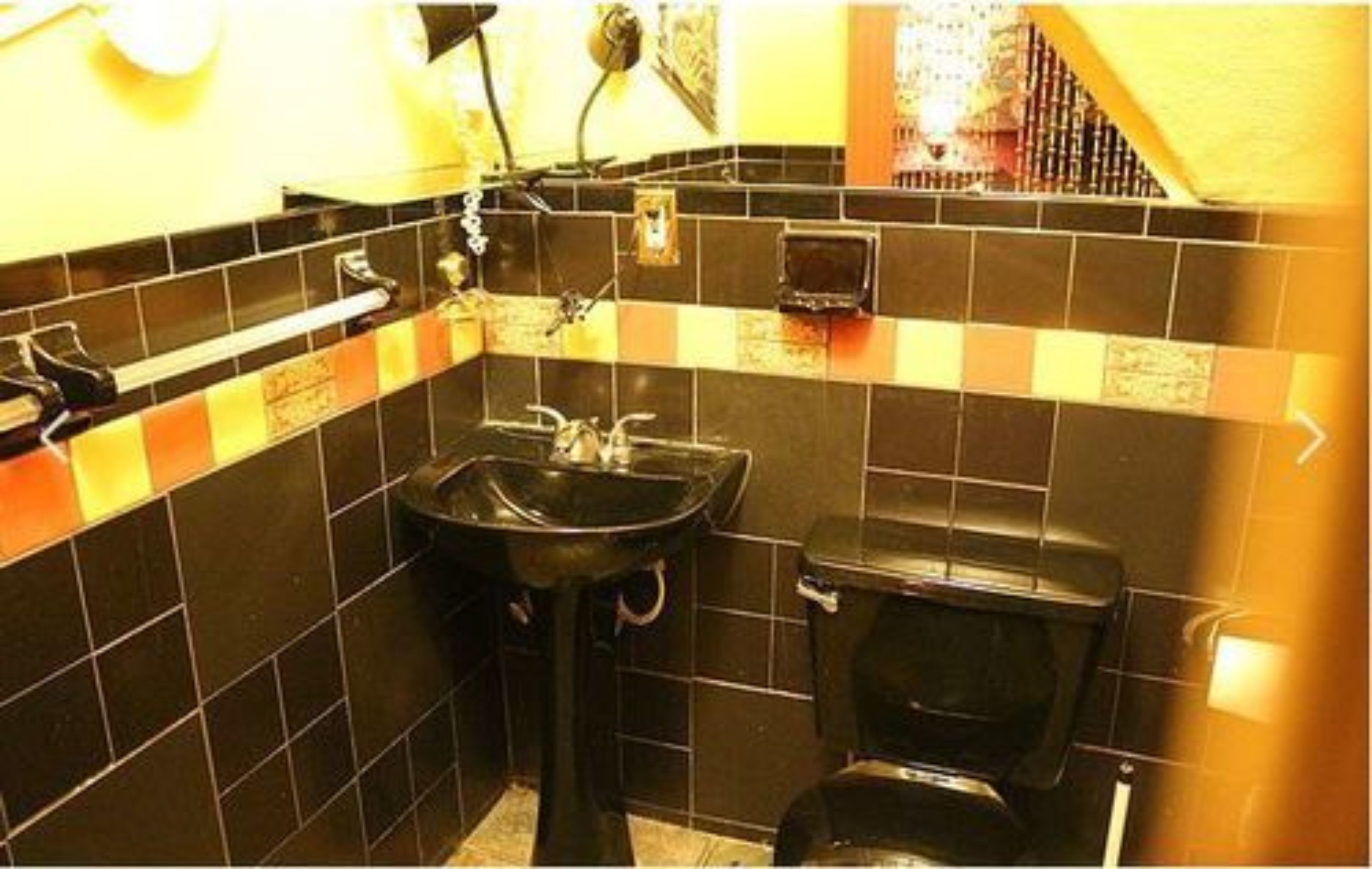 Un baño pequeño con un lavabo negro, un inodoro y un espejo.