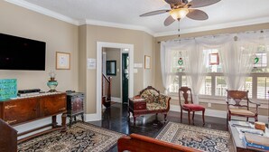 A spacious living room with a ceiling fan, a large flat-screen TV, and a wooden coffee table. - The Wayward Traveler's Inn (Mims)