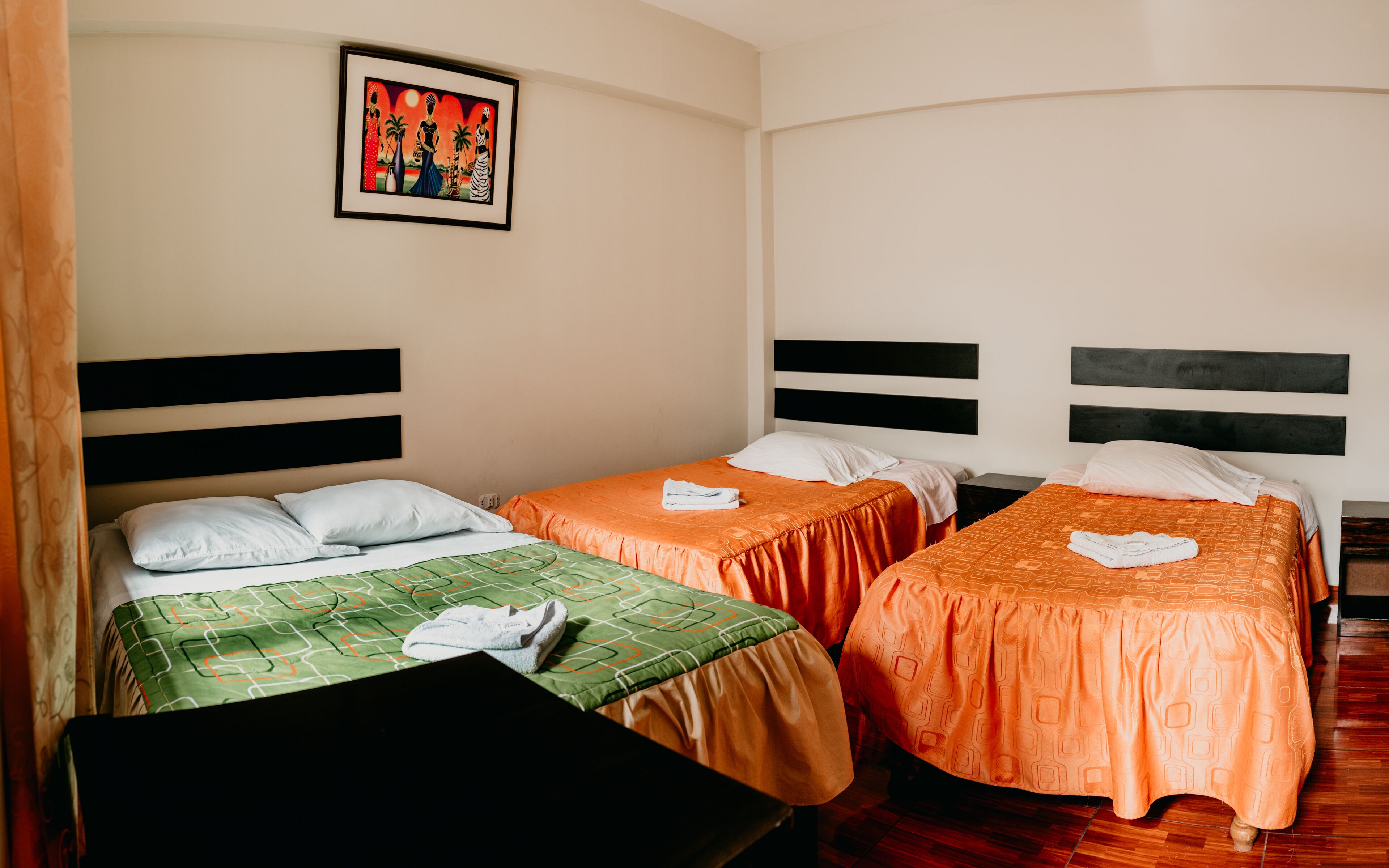 Une chambre d’hôtel avec deux lits simples, un tableau encadré au mur et un plancher en bois.