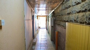 A narrow hallway with tiled flooring, a stone wall on one side, and a yellow door on the other. - West Park (Nairobi)