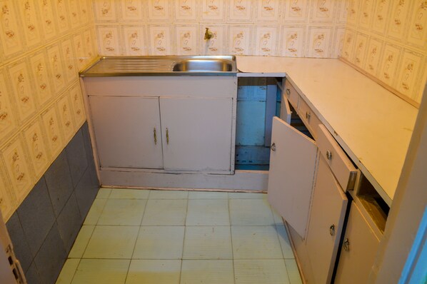 A small kitchen with a sink, cabinets, and a tiled floor. - West Park (Nairobi)