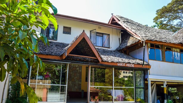 A guest house with a thatched roof, large windows, and a stone facade. - West Park (Nairobi)