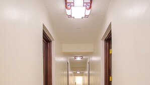 Un corridoio con pareti bianche, pavimento in marmo e porte in legno.