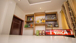Angolo bar con scaffali pieni di bottiglie e un cartello con la scritta 'ABILLION REASONS TO LIVE IN AFRICA'.
