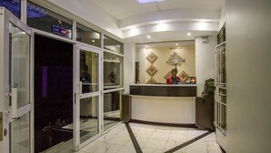 Una hall d'albergo con la reception, un orologio a parete e un cartello che indica che il terminale di pagamento con carta di credito non è operativo.