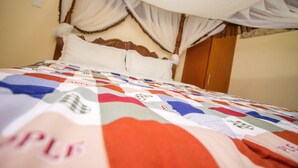 A bed with a quilt, a wooden headboard, and a canopy. - Shamz Hotel Isiolo (Isiolo)
