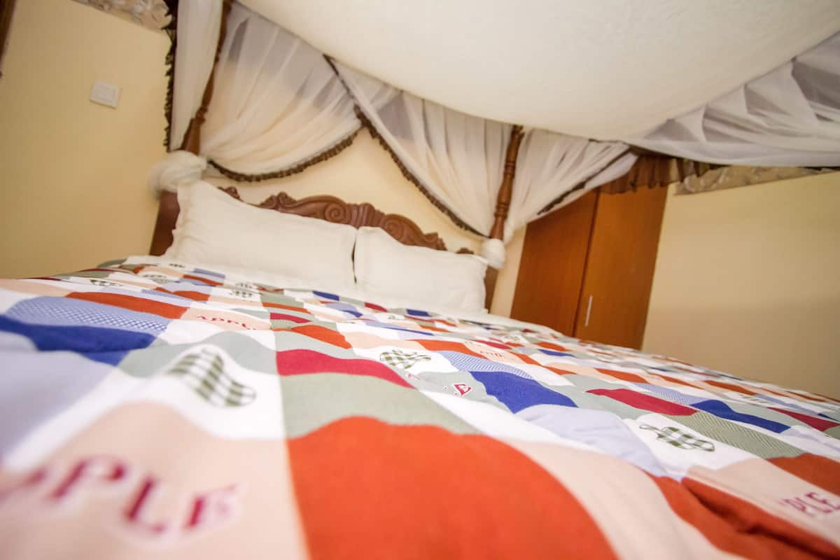A bed with a quilt, a wooden headboard, and a canopy.