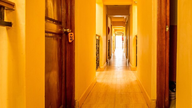 A long, narrow hallway with wooden doors and yellow walls. - Shamz Hotel Isiolo (Isiolo)