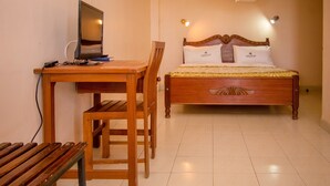 A bedroom with a wooden bed, a desk with a computer, and a chair.