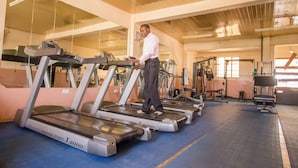 A gym with treadmills, weight machines, and a blue mat floor.