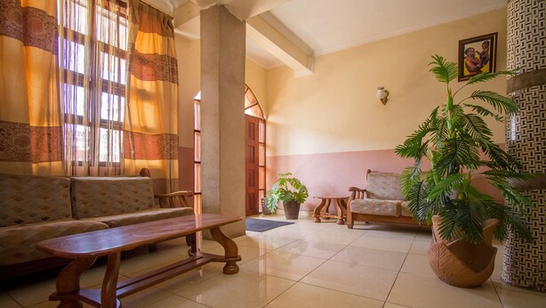 A spacious living area with a sofa, wooden bench, and potted plants.