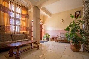 Uma sala de estar ampla com sofá, banco de madeira e plantas em vasos.