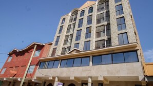 A multi-story building with a mix of brick and stone facades, large windows, and a prominent entrance with a sign.