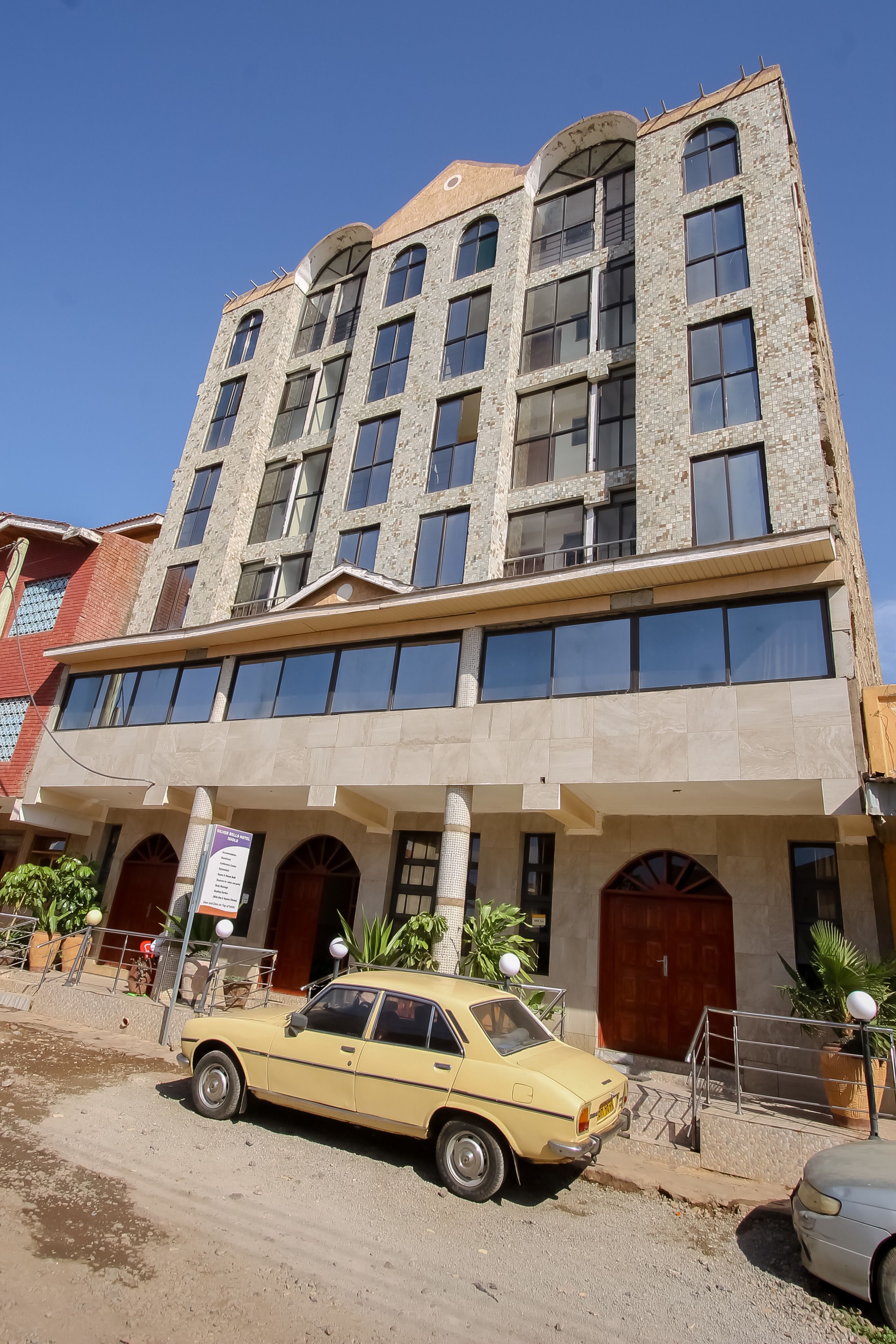 Un edificio de varios pisos con fachada de piedra, ventanas amplias y techo plano.