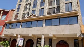 Un edificio de varios pisos con fachada de piedra, ventanas amplias y techo plano.