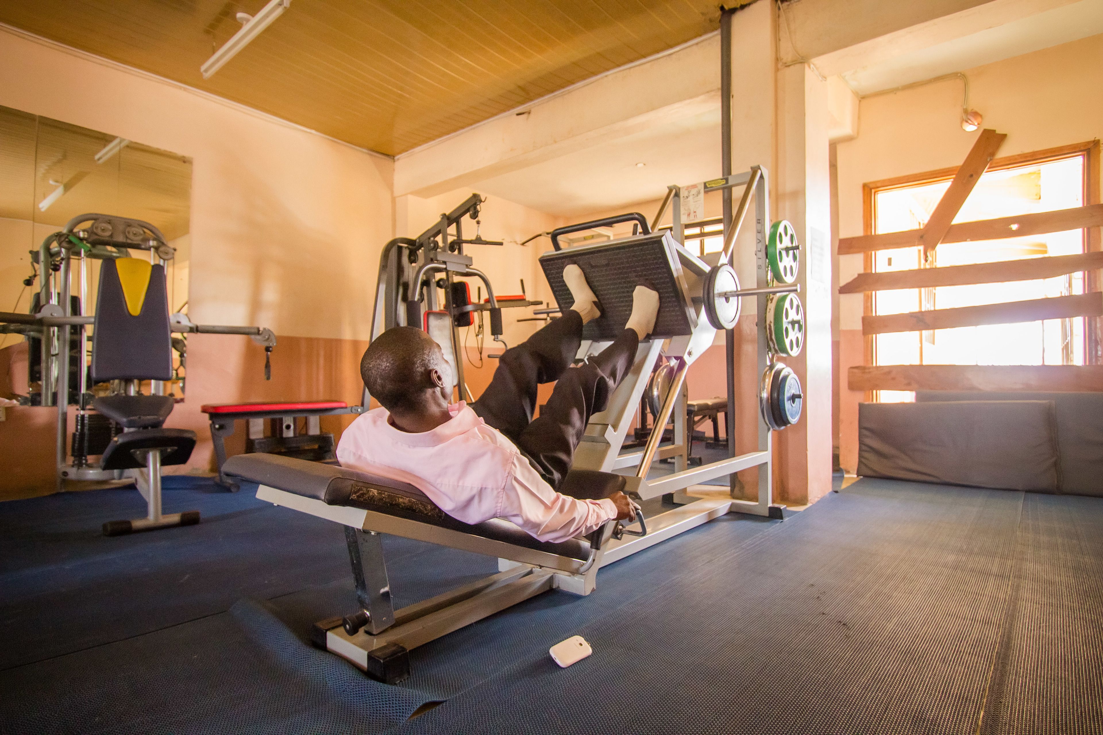 A gym with exercise equipment, a bench, and a mirror.