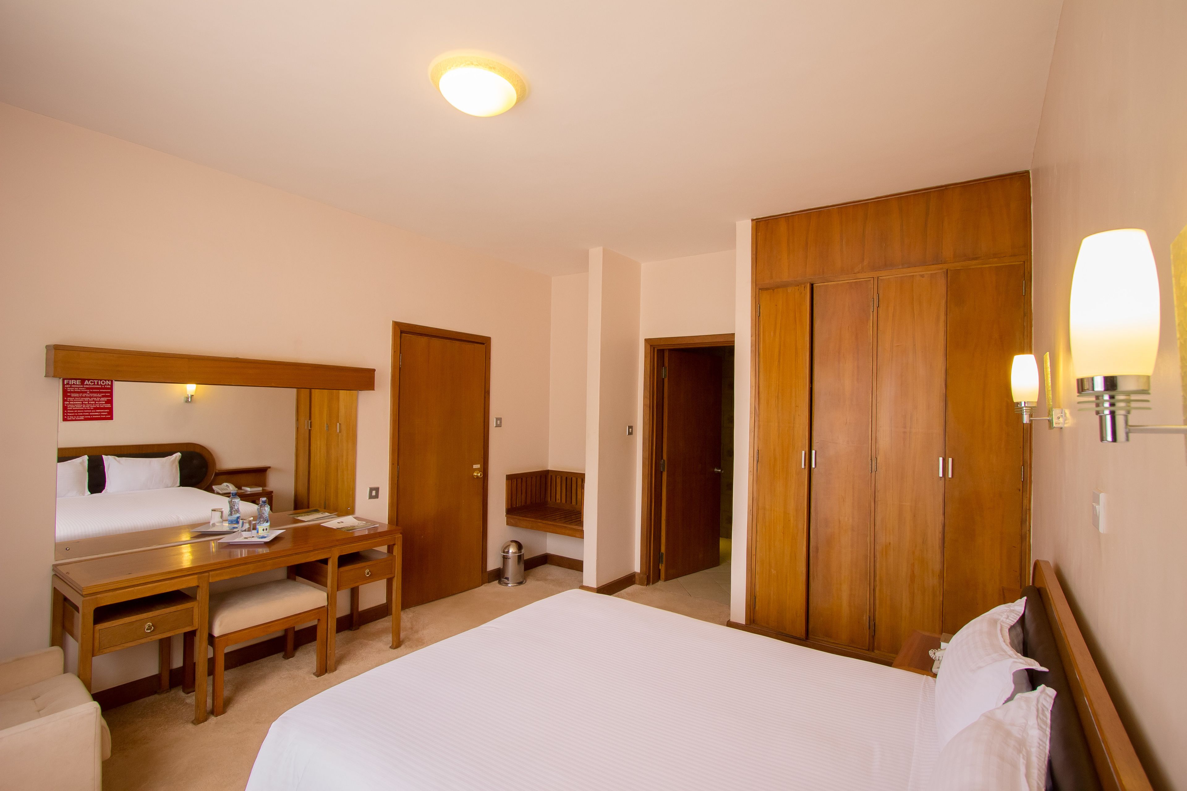 Una habitación de hotel con una cama, un escritorio, una silla y un armario.