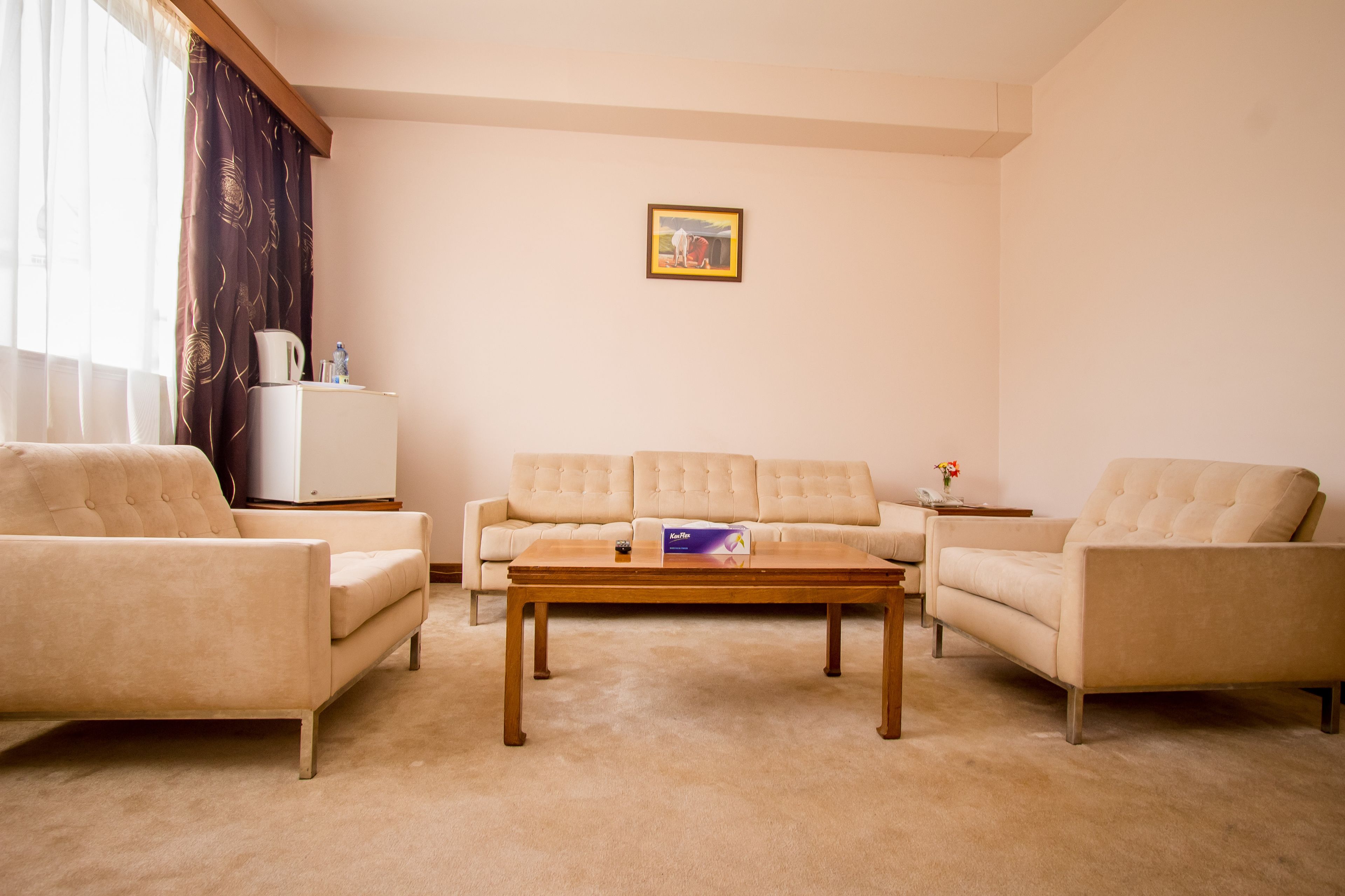A living room with a beige sofa set, a wooden coffee table, and a small side table.