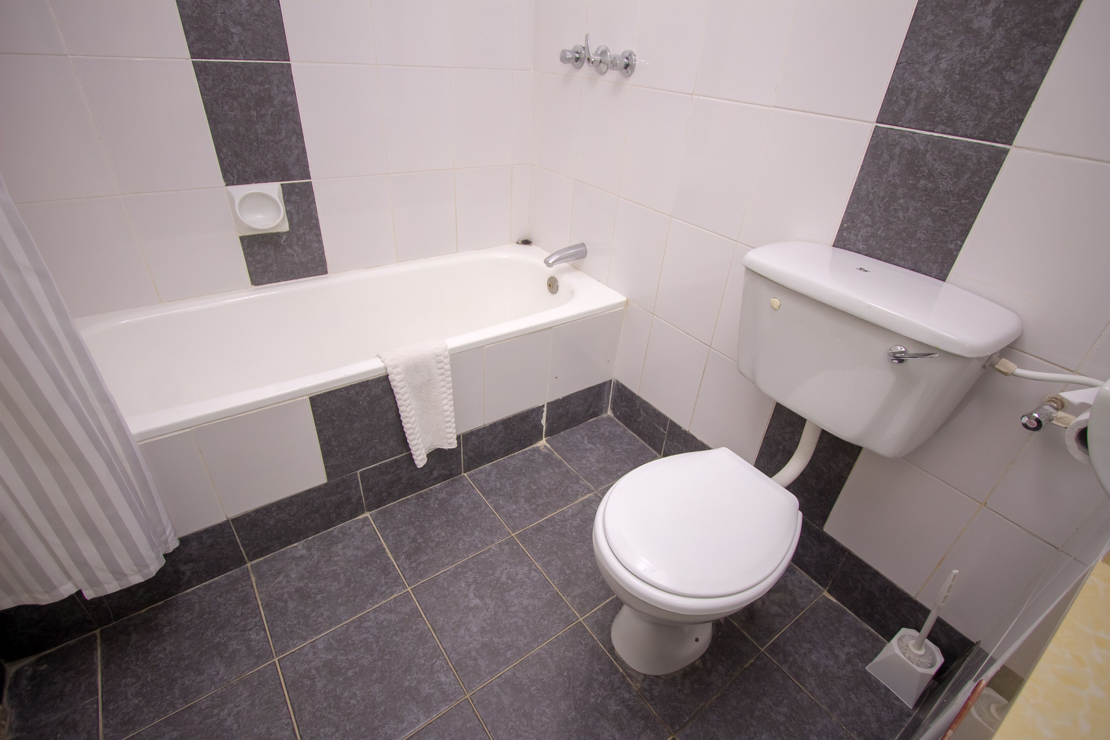 A bathroom with a bathtub, toilet, and a hand dryer.
