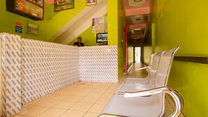 Un área de espera con mostrador de recepción, sillas y piso de baldosas.