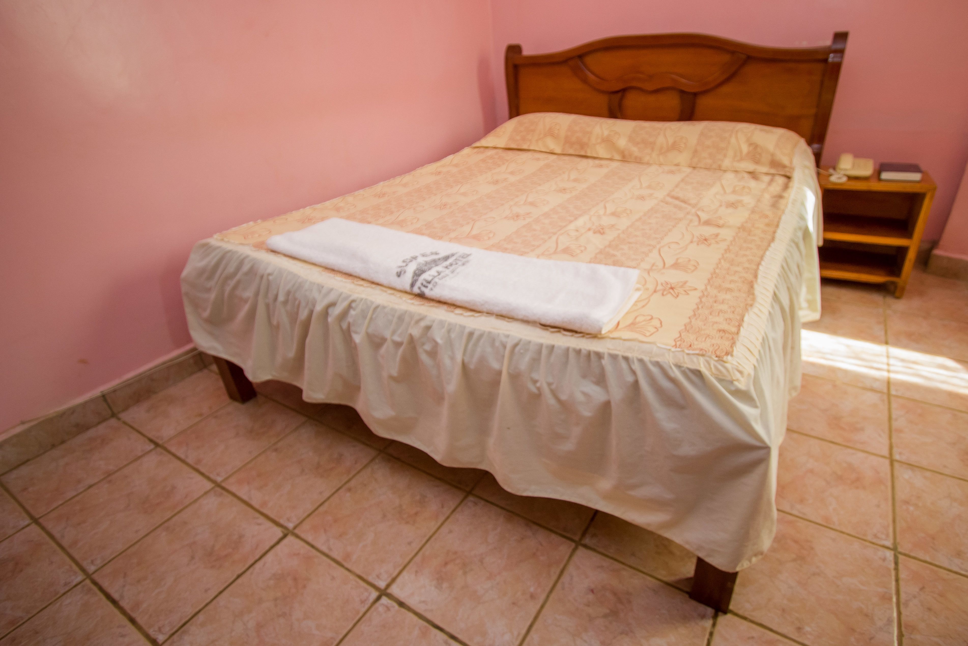A bed with a white bedspread and a folded white towel on it.