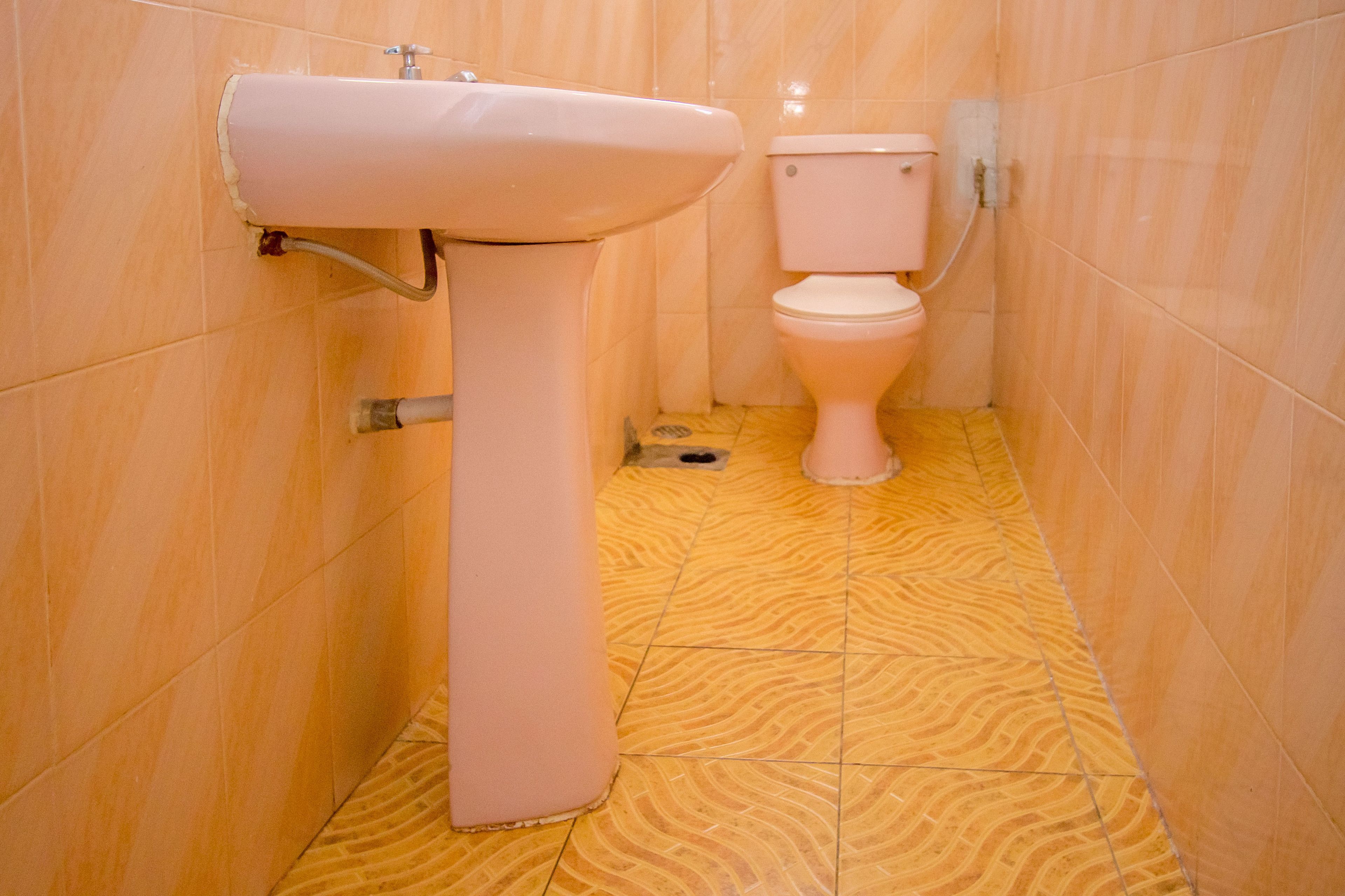 Une salle de bain avec un lavabo et des toilettes, des murs carrelés et un sol à motifs.