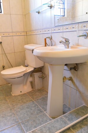 A bathroom with a toilet, sink, and tiled floor.