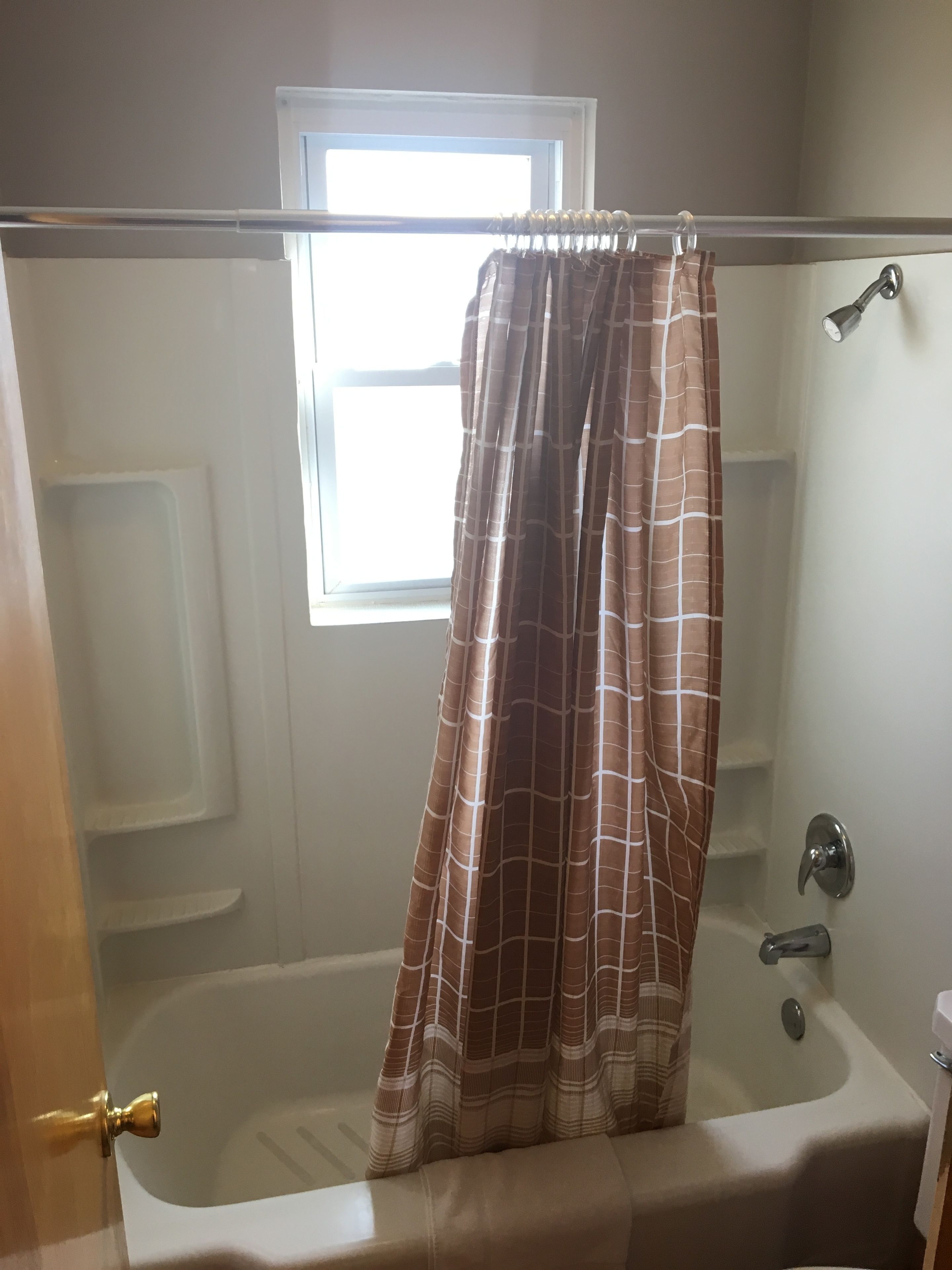 Un baño con bañera, cortina de ducha y ventana.