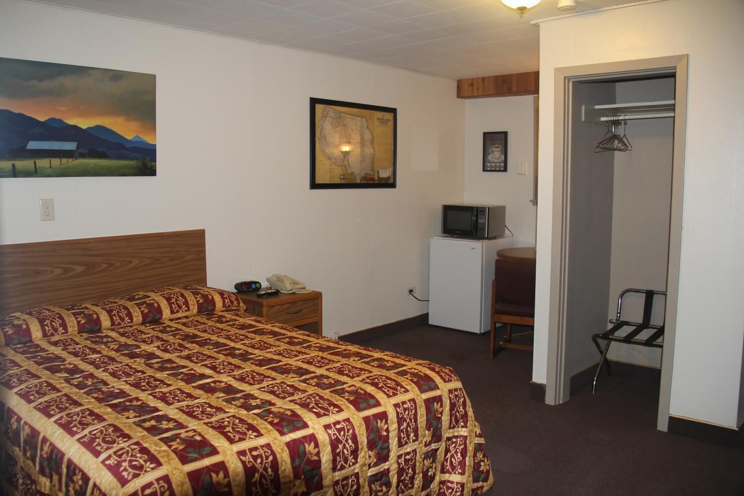 Hotelkamer met een bed, bureau, stoel, magnetron en een deur.