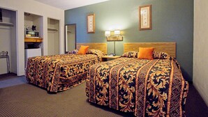 Ein Hotelzimmer mit zwei Betten, einem Schreibtisch, einer Mikrowelle und einem kleinen Kühlschrank.
