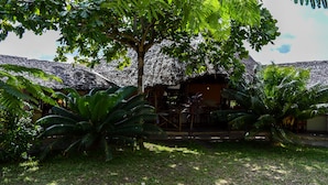 A thatched-roof building with a covered outdoor seating area and lush tropical vegetation. - Platinum Hotel (Mombasa)