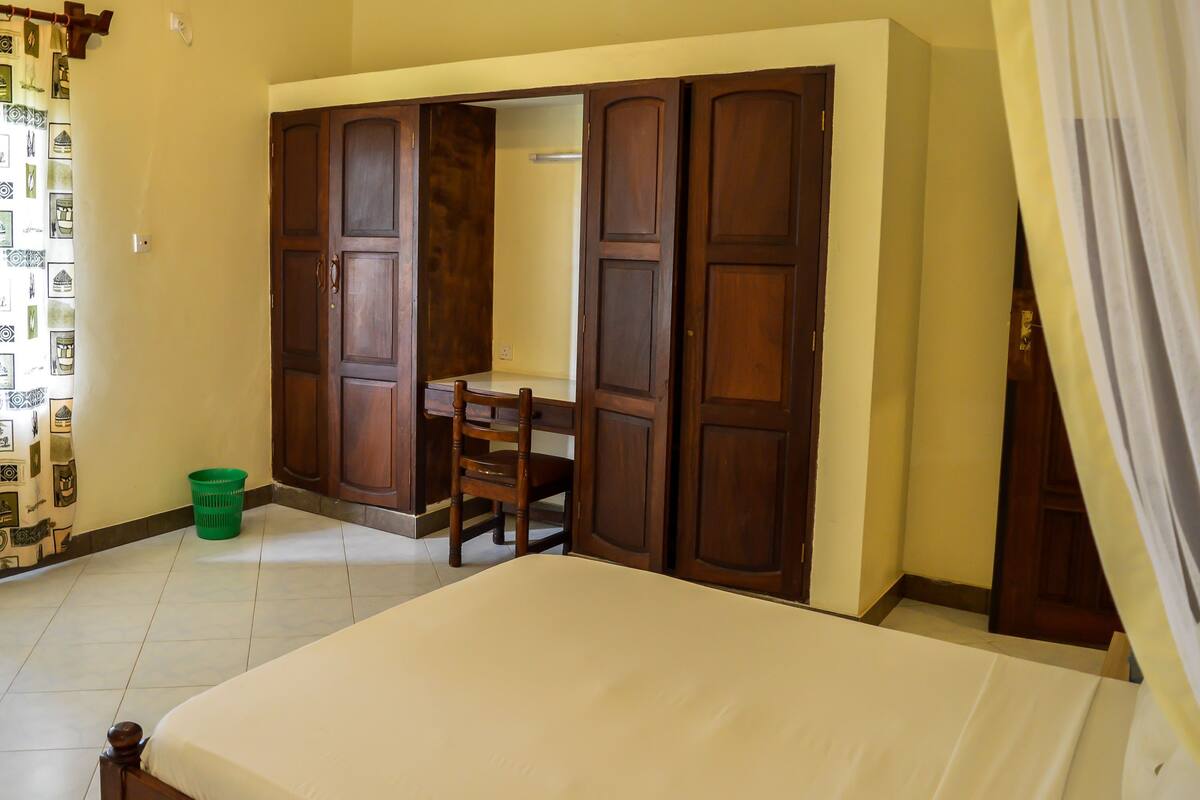 Un dormitorio con cama, escritorio y armario.