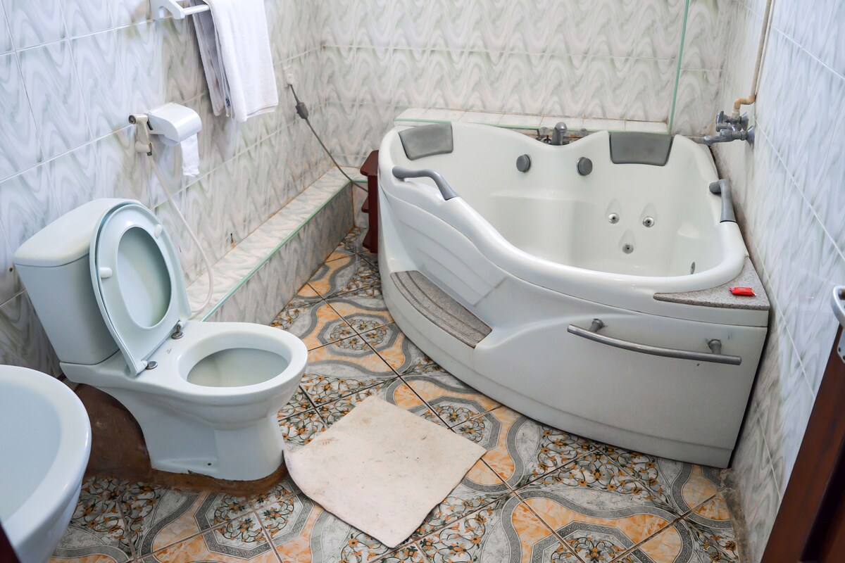 A bathroom with a toilet, a bathtub, and patterned floor tiles.