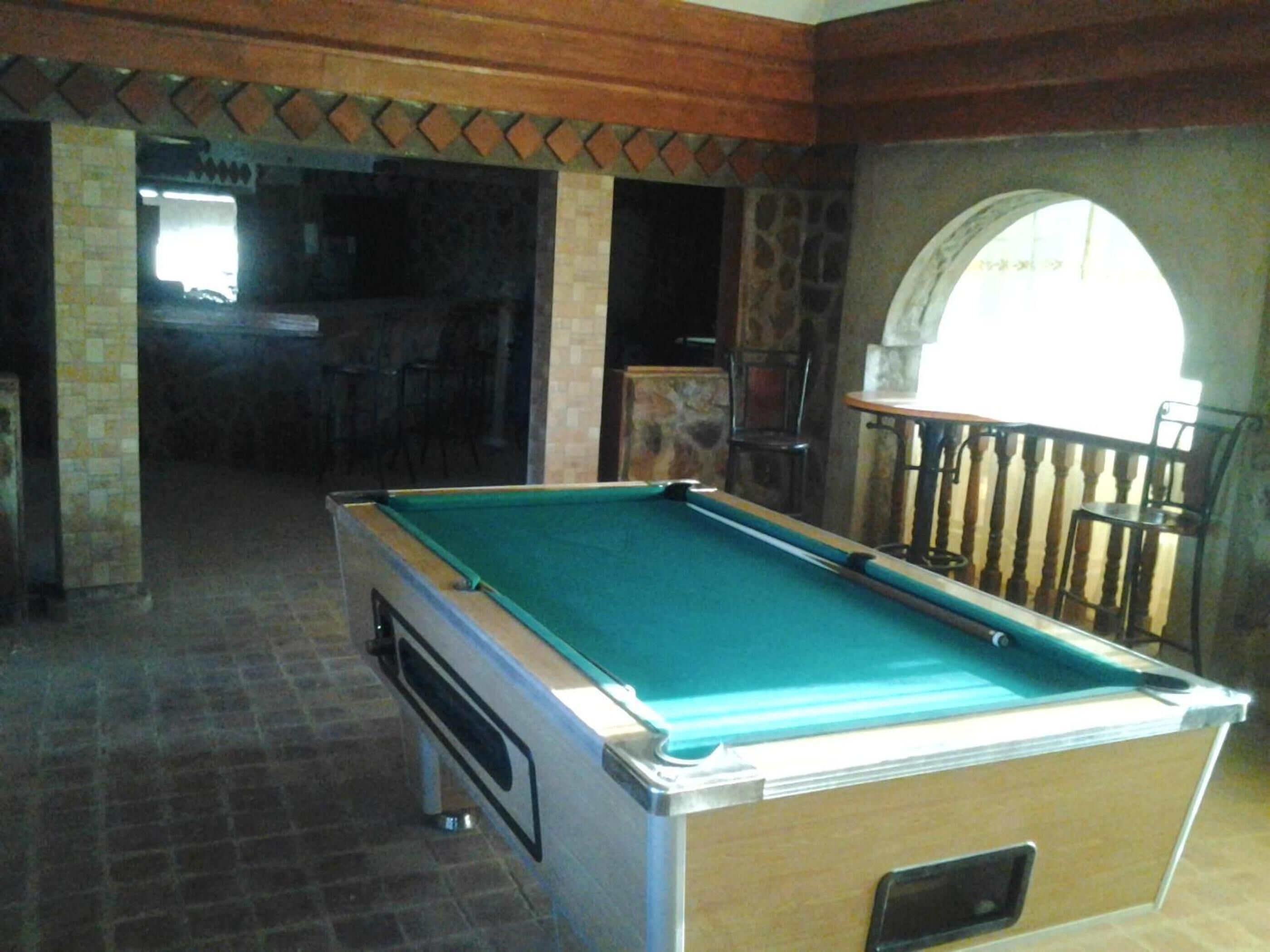 A pool table in a room with stone walls and a wooden ceiling.